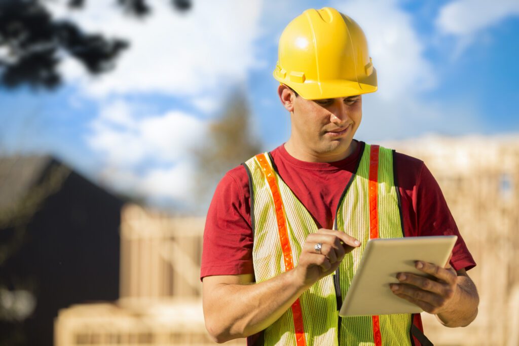 A construction worker using a tablet to review HVAC inspection notes on the jobsite