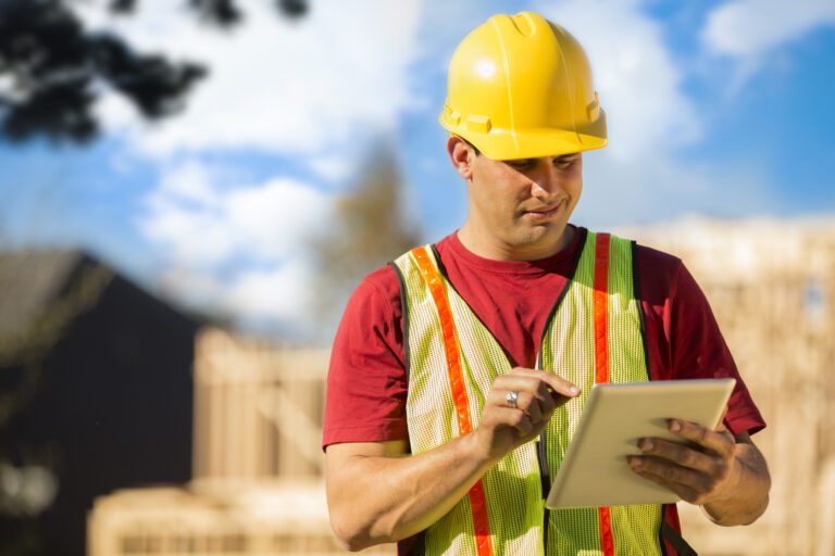 A construction worker using a tablet to review HVAC inspection notes on the jobsite