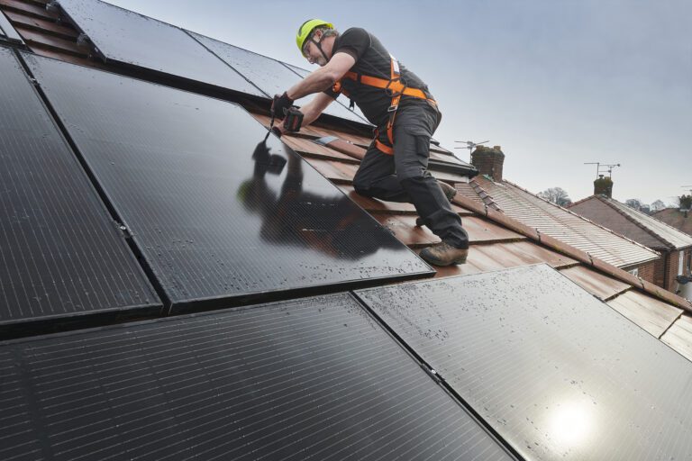 Man installing solar panels on roof of house