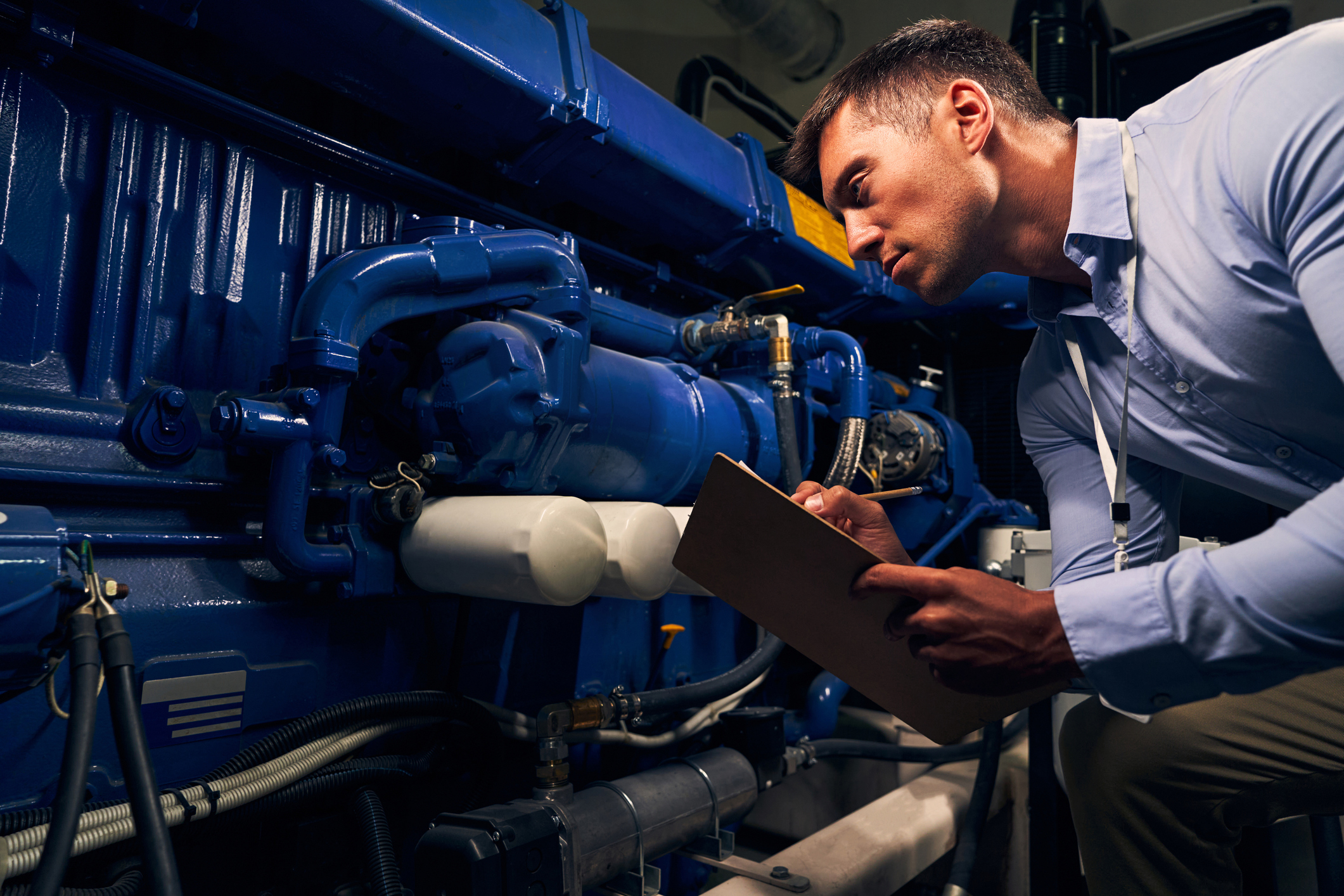 A maintenance technician assessing a generator using a generator inspection checklist on a clipboard.