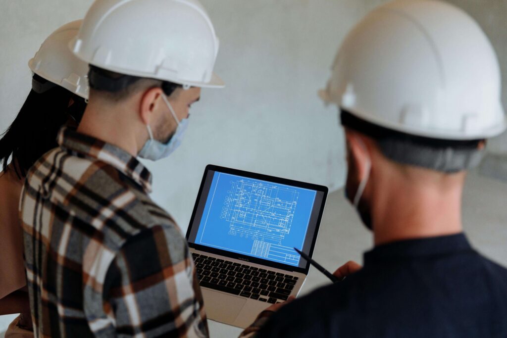 Contractors reviewing building blueprints on a laptop during a remote virtual inspection