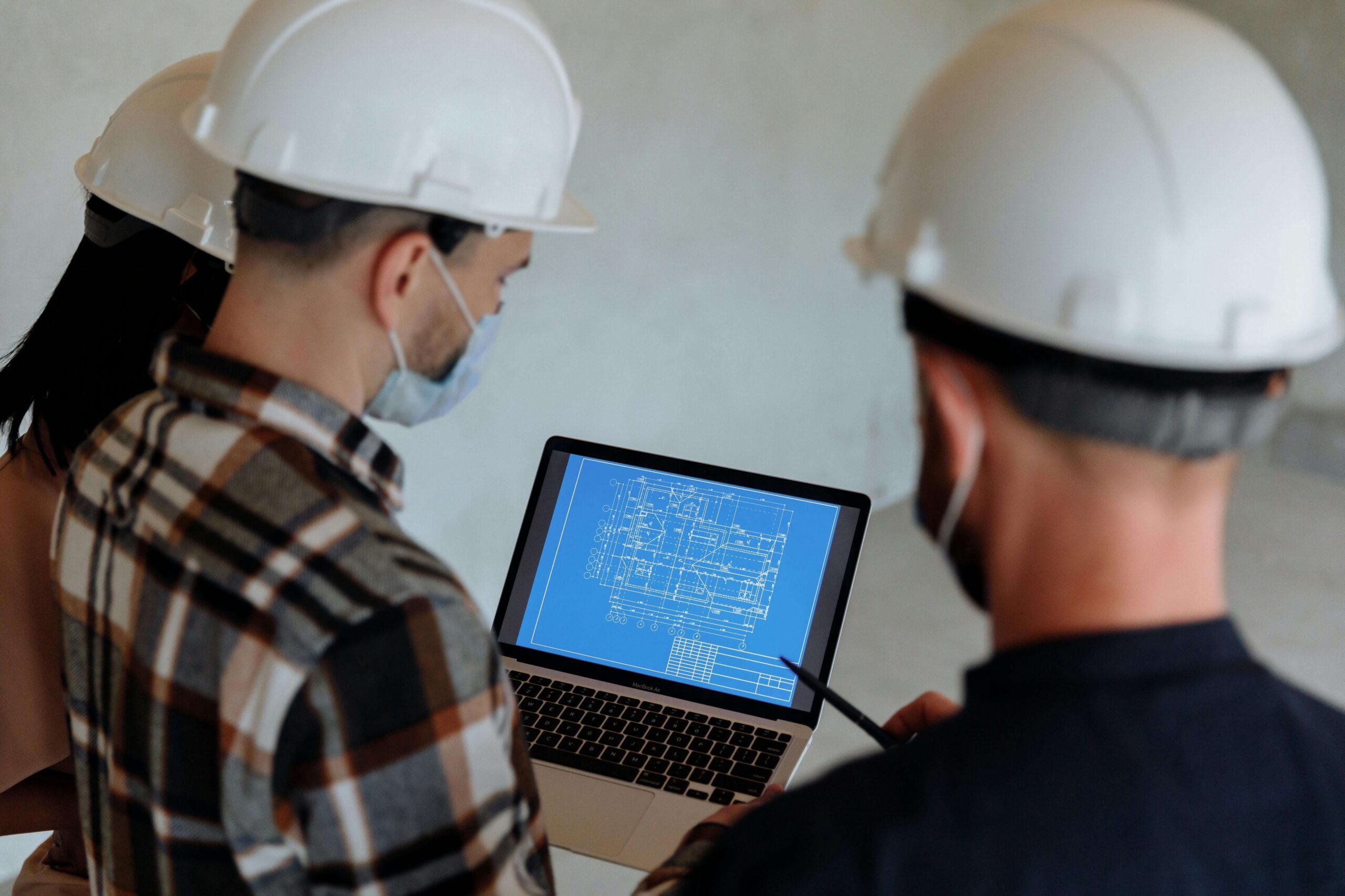 Contractors reviewing building blueprints on a laptop during a remote virtual inspection