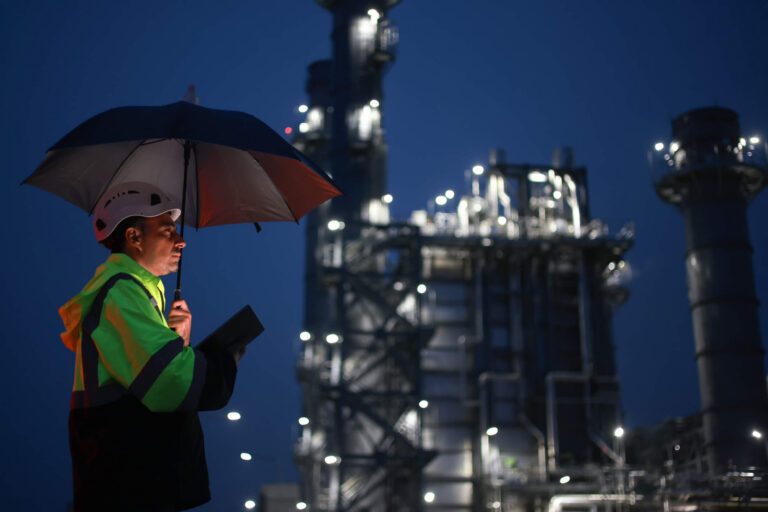 Contractor holding a tablet and umbrella during a storm damage inspection at a commercial facility at nigh