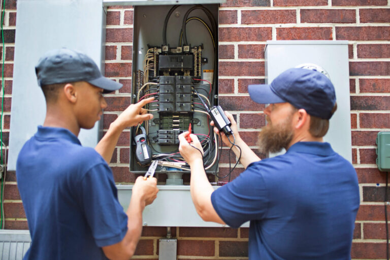 Electricians using a multimeter to inspect a panel during an electrical inspection